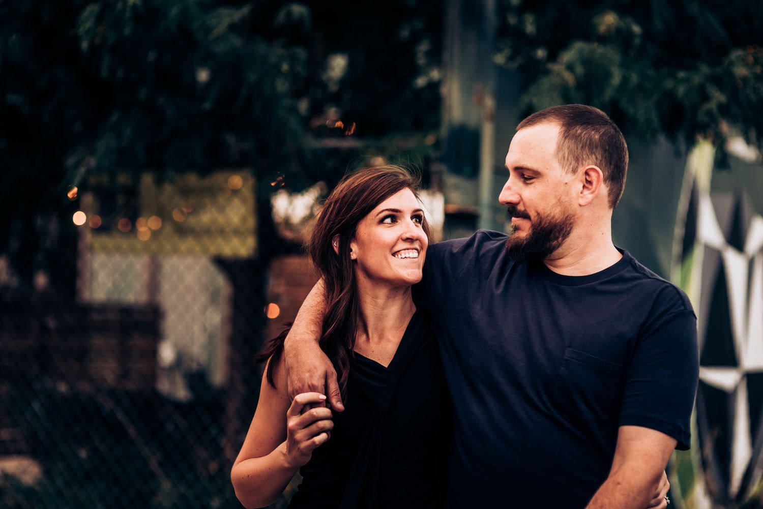 Happy couple laughing together outdoors in casual attire.