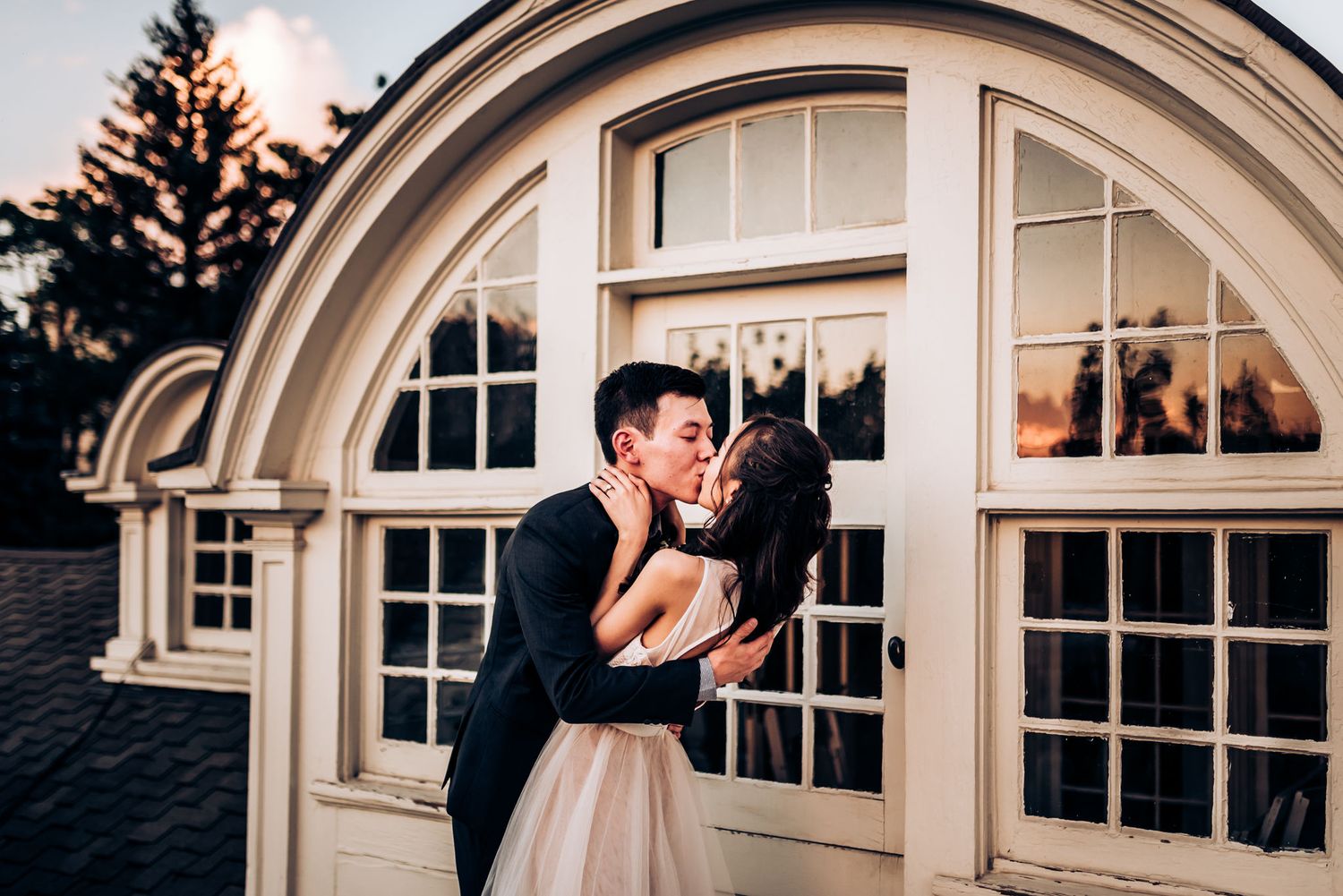 Romantic wedding photo against arched window architecture at twilight.