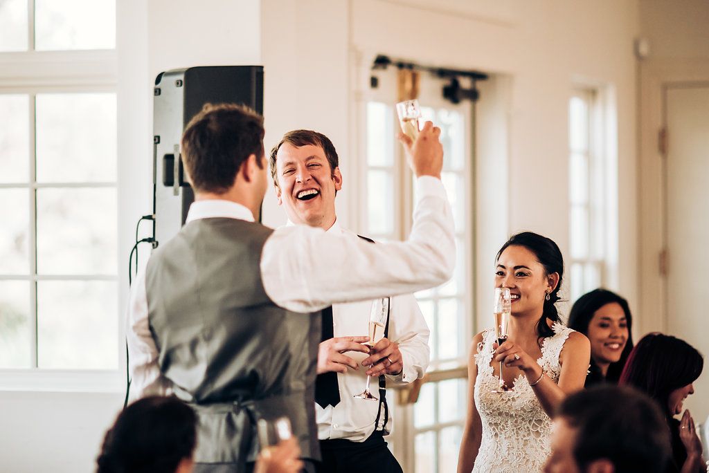 Joyous celebration moment during wedding reception speeches.