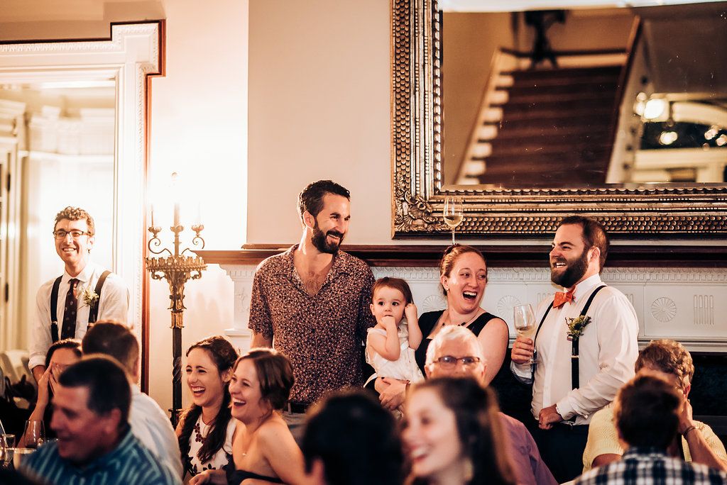 Wedding reception guests share laughs and stories during celebratory speeches.