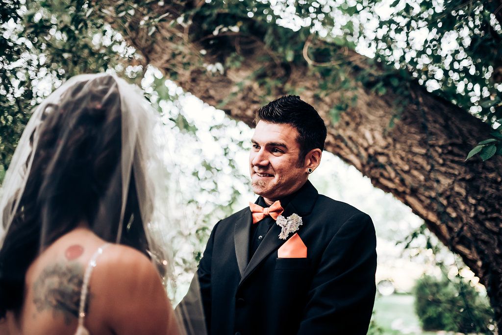 An emotional wedding moment captured under tree branches during an outdoor ceremony.