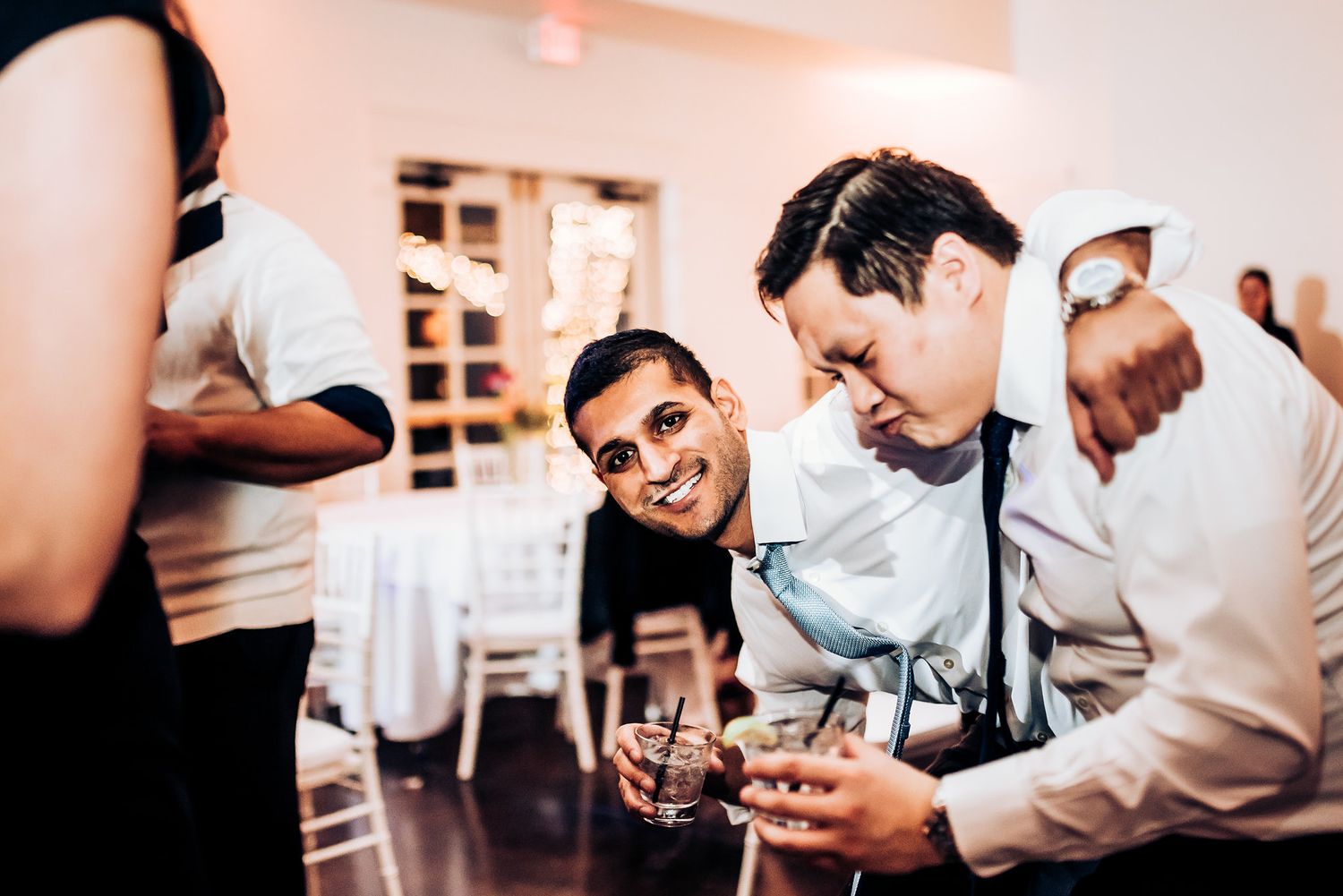 Party guests share drinks and laughs at an elegant indoor reception.
