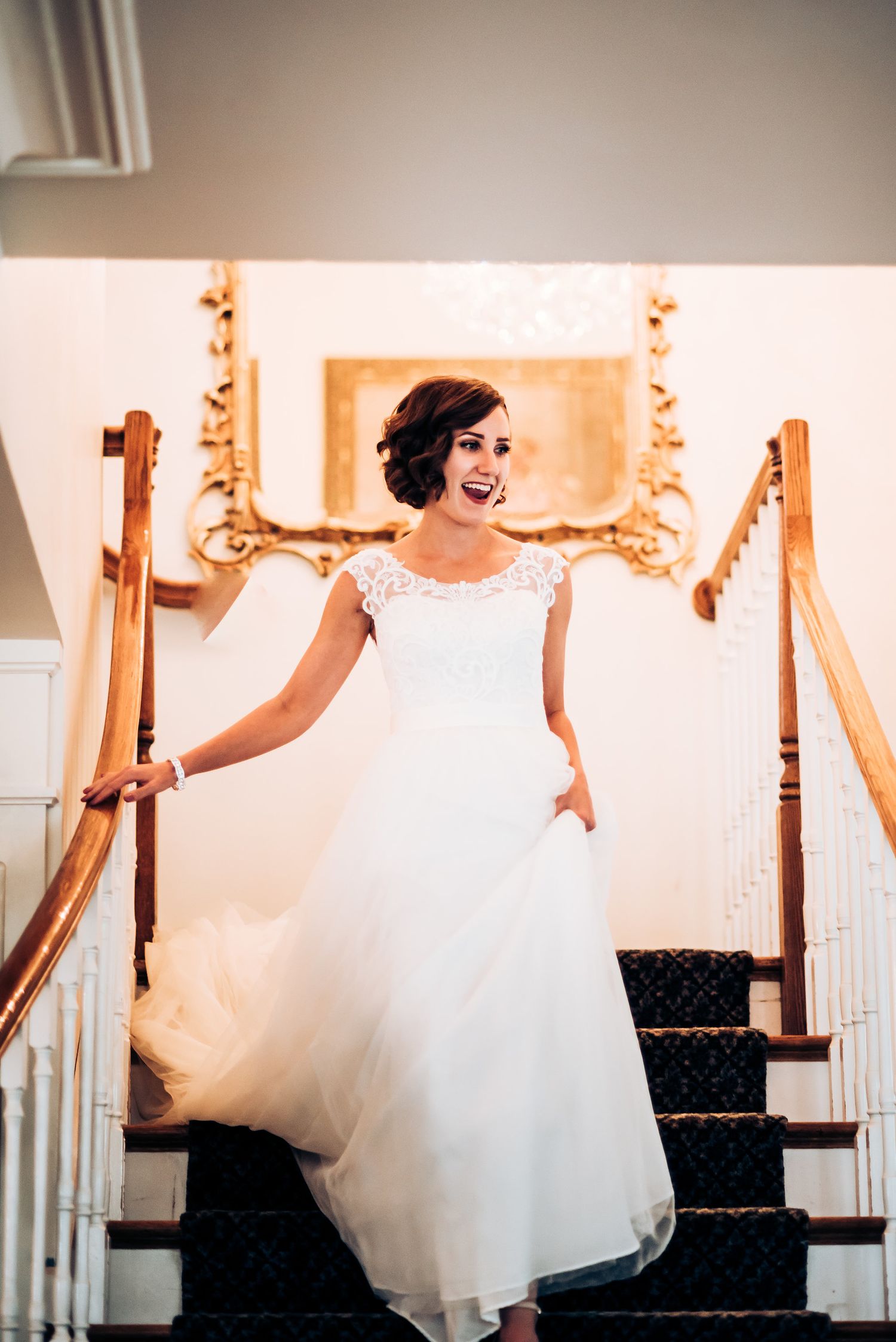 A flowing white wedding gown captured on an elegant staircase with warm lighting.