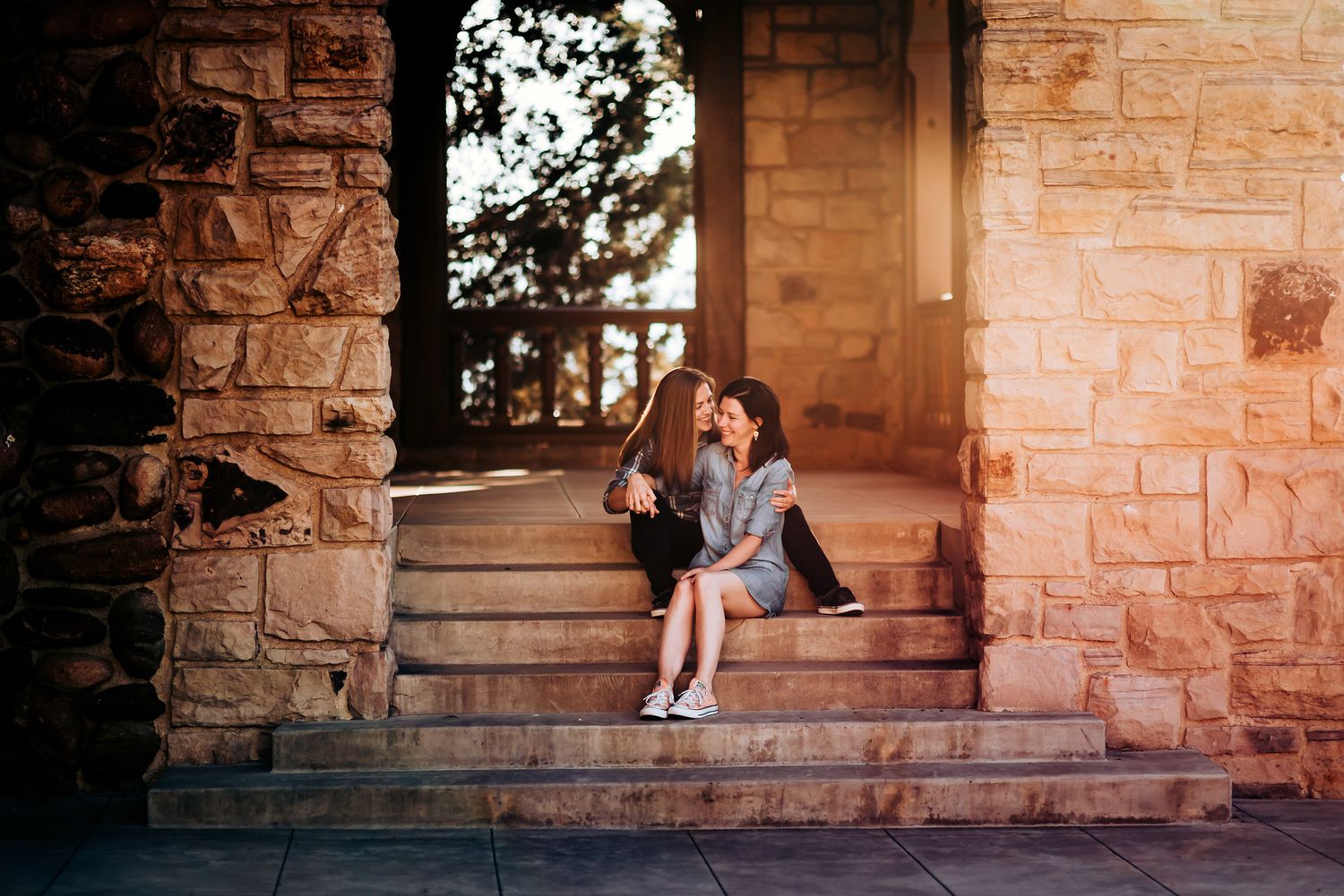 Two people sit together on stone steps of a historic building during golden hour.