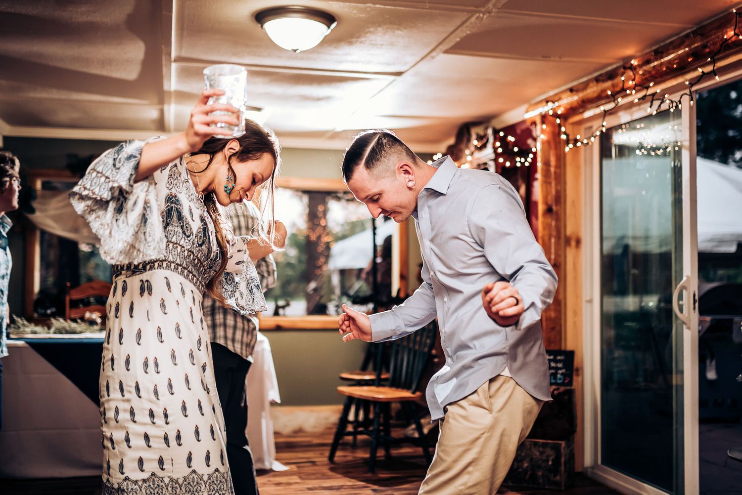 Dancing and laughing together at an indoor celebration with string lights overhead.