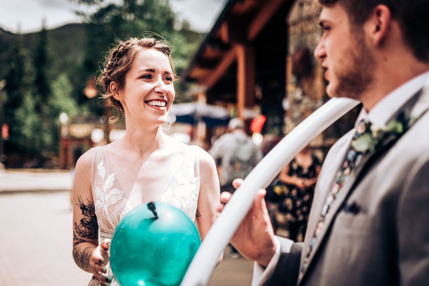 Couple shares lighthearted moment with green balloon during outdoor wedding celebration.