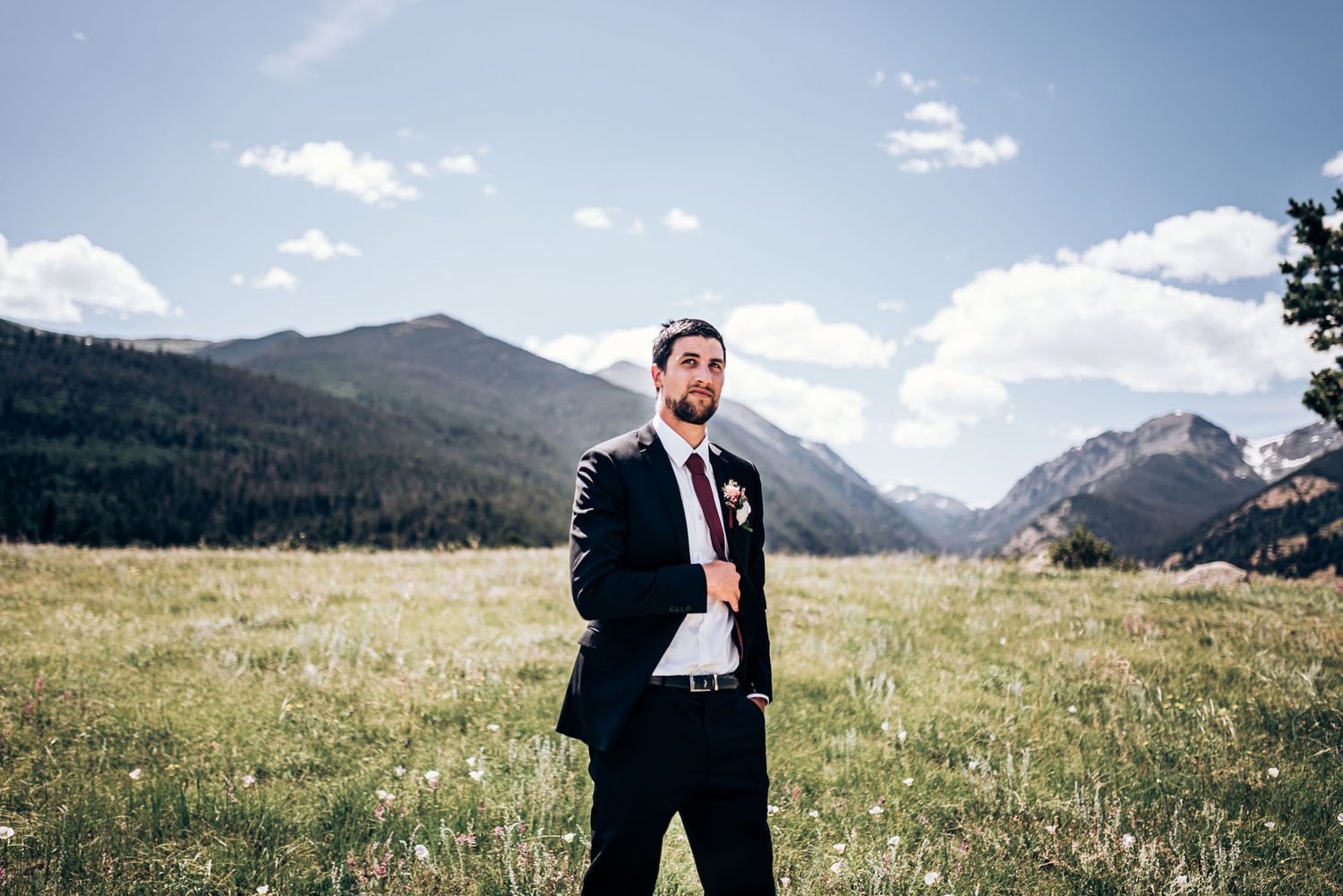 A classic black suit stands out against rugged mountain landscape on a sunny day.