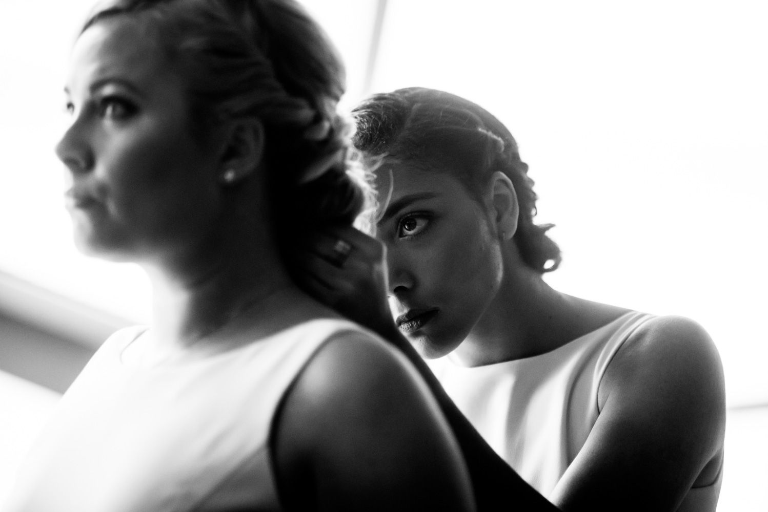 Dramatic black and white portrait of two people in formal wear positioned back-to-back.