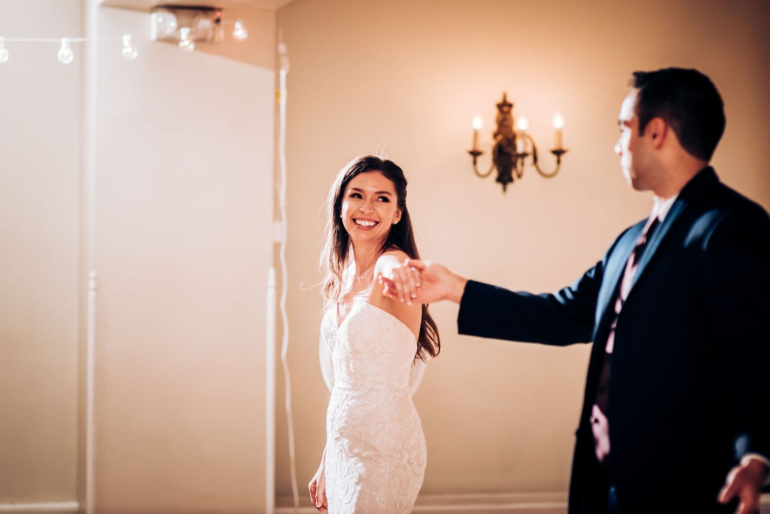 A couple shares their first dance in an elegant room with a vintage chandelier.