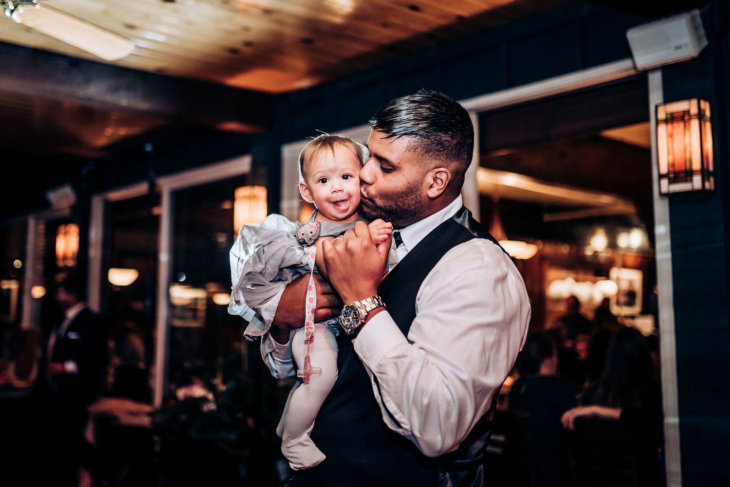 Tender moment between parent and young child during evening wedding reception.