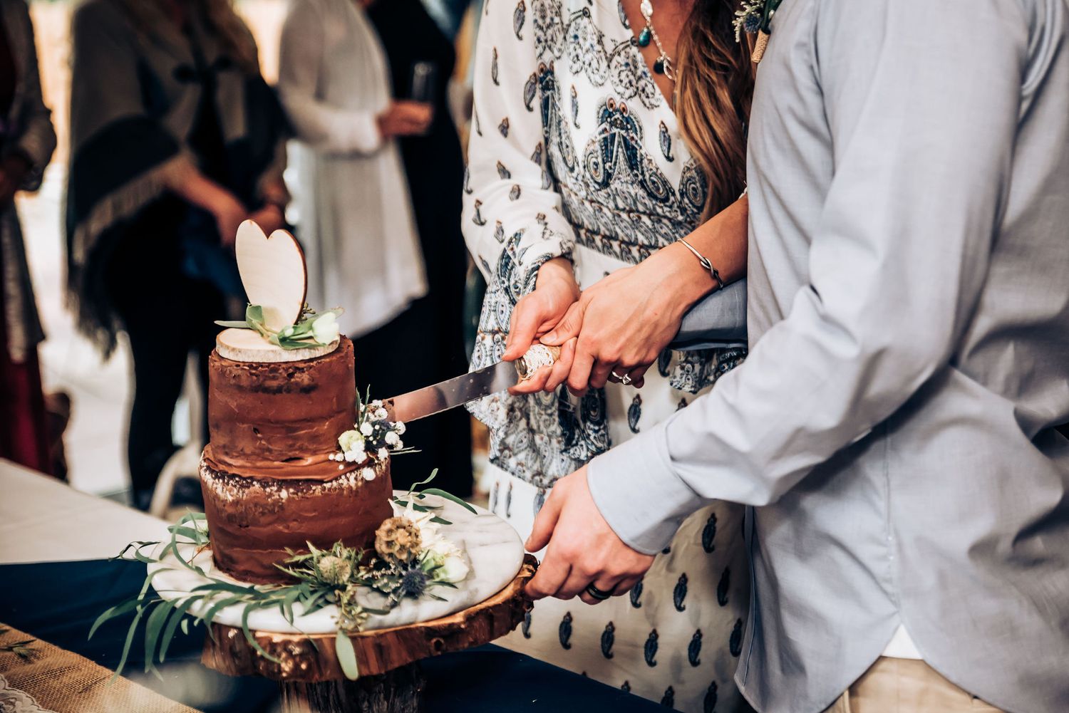 A chocolate wedding cake being cut at an intimate reception celebration.