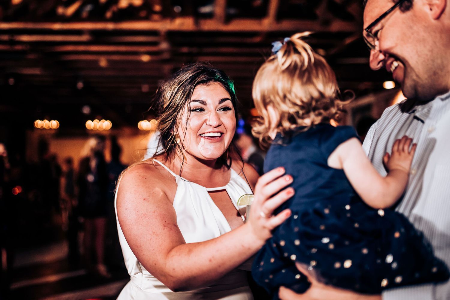 Joyful celebration during wedding reception with dancing and laughter in a rustic indoor venue.