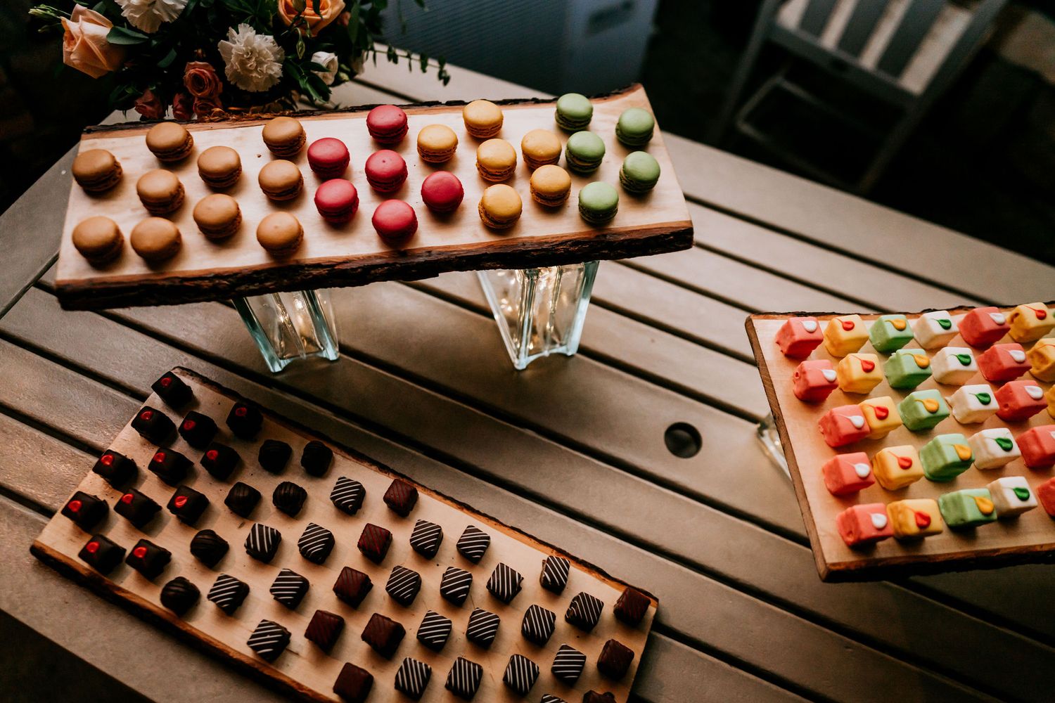 Colorful array of mini desserts displayed on wooden serving boards at a wedding reception.
