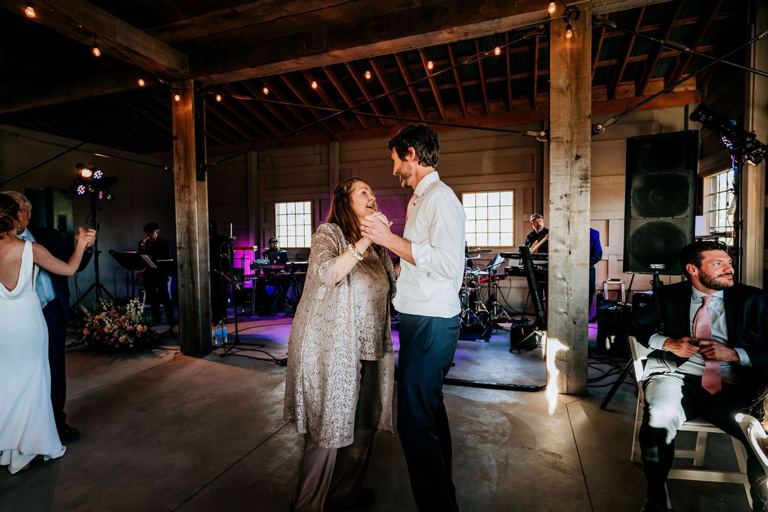A couple shares their first dance in a rustic barn venue during their wedding reception.