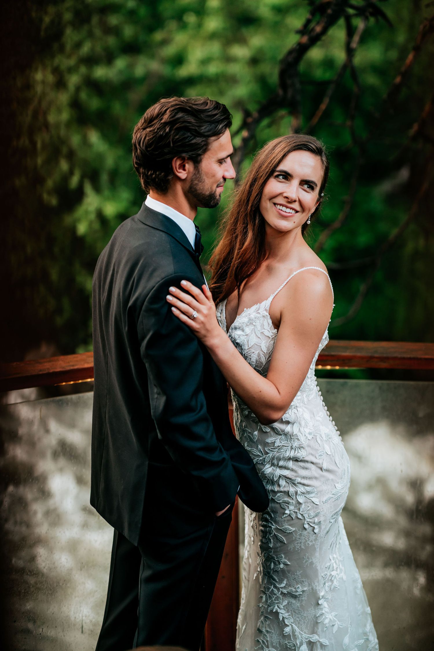 Intimate moment between couple in formal attire against lush green garden background.