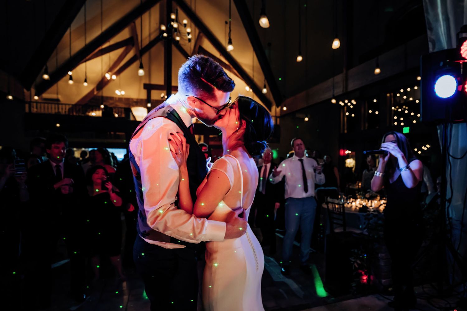 Couple sharing an intimate slow dance moment under atmospheric lighting at an indoor venue.
