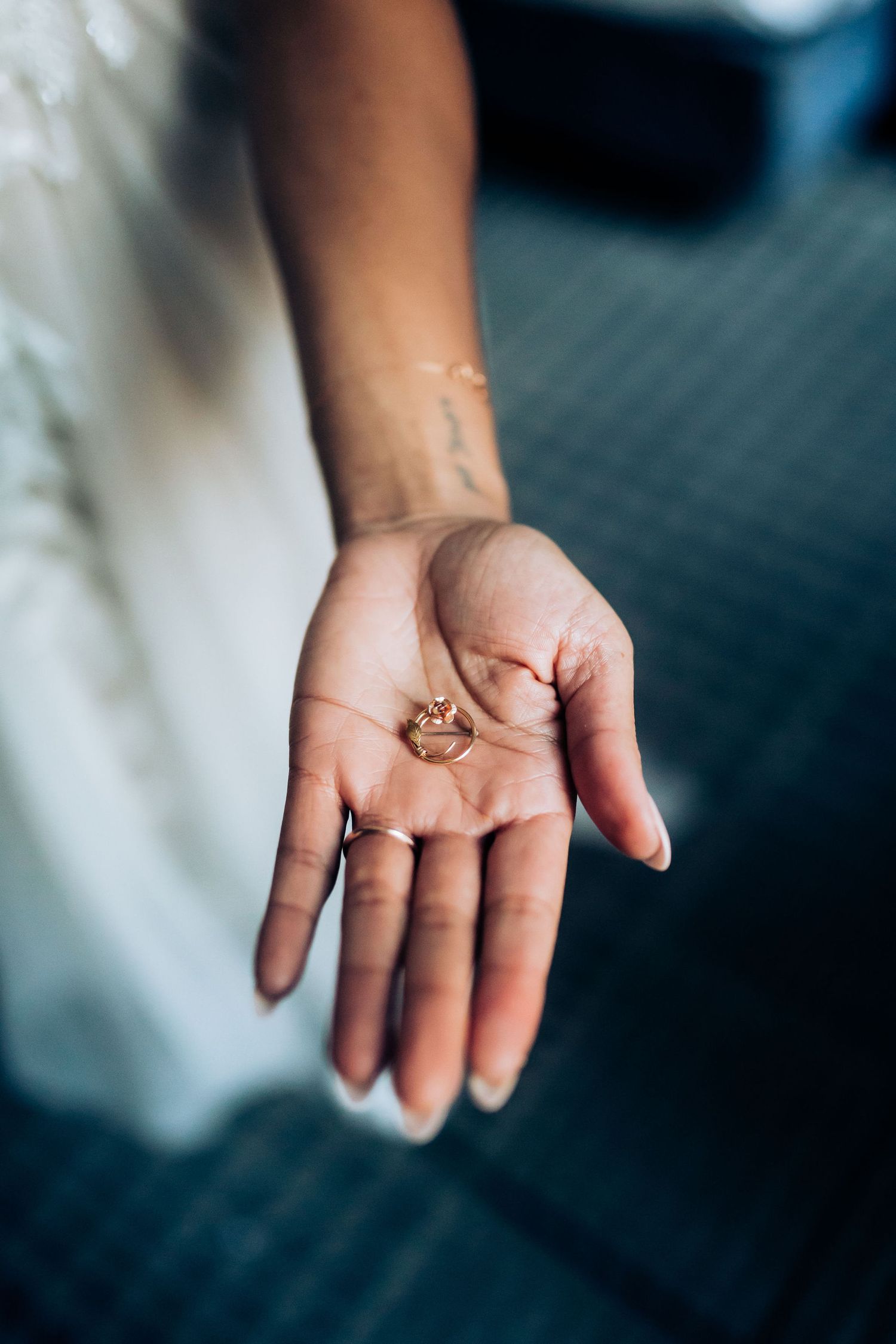 A delicate rose gold wedding ring rests in an open palm against white fabric.