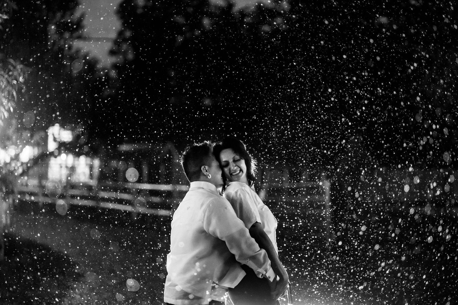 A romantic black and white photo of a couple embracing in the rain.