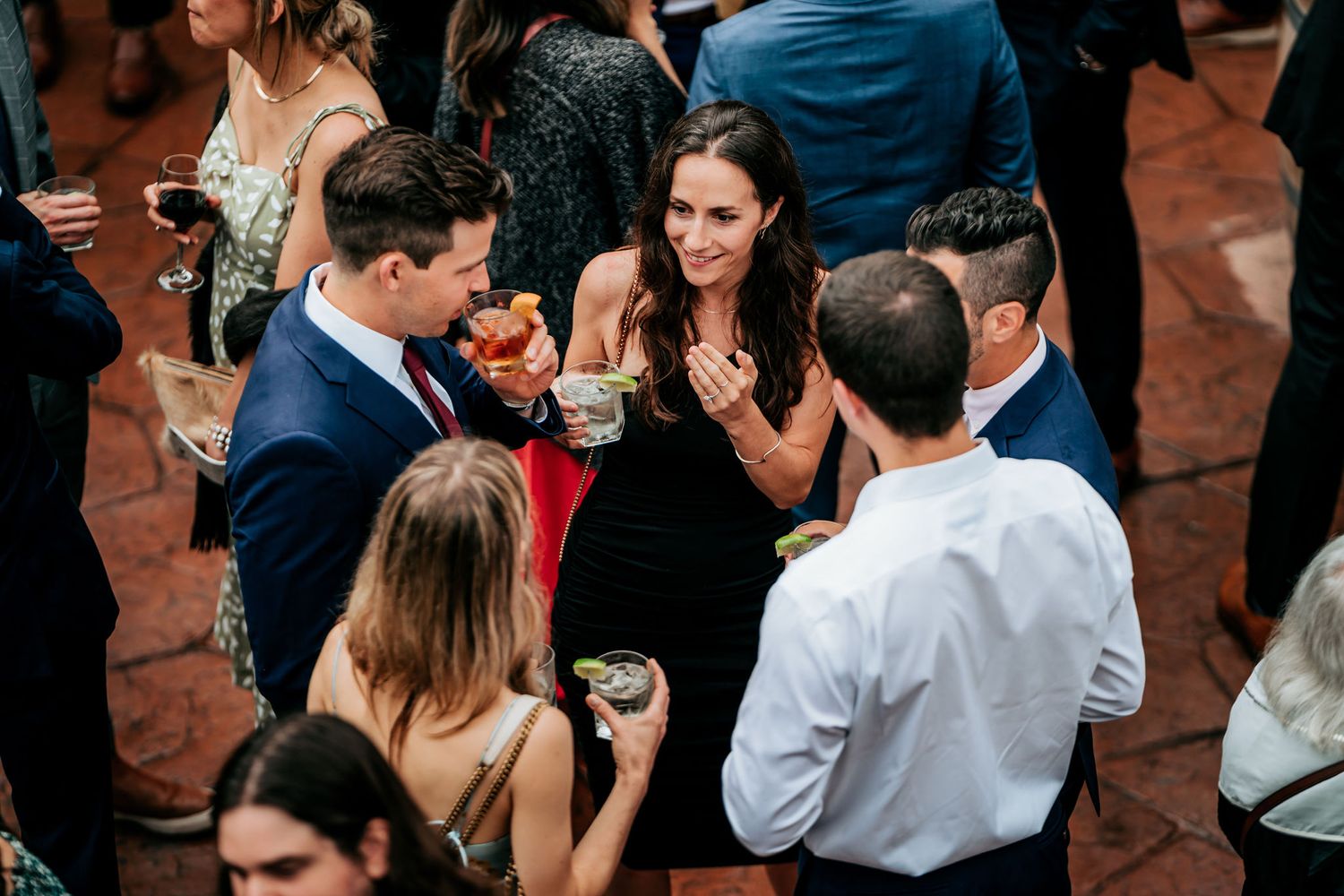 A group of elegantly dressed guests socialize and mingle at an evening wedding reception.
