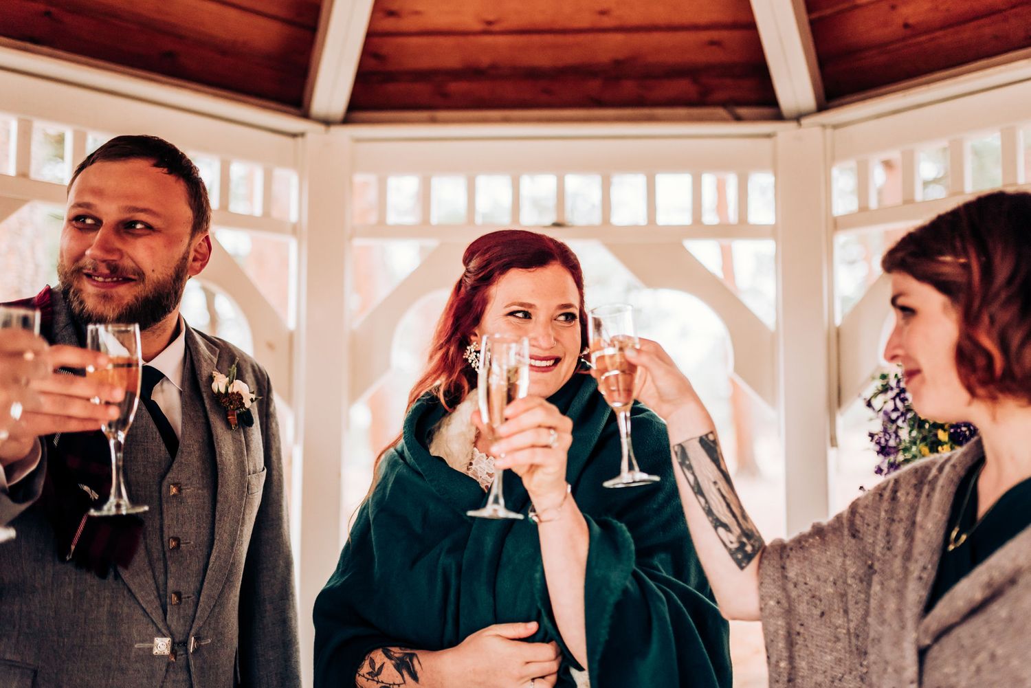Three friends enjoying champagne together in an elegant gazebo setting.