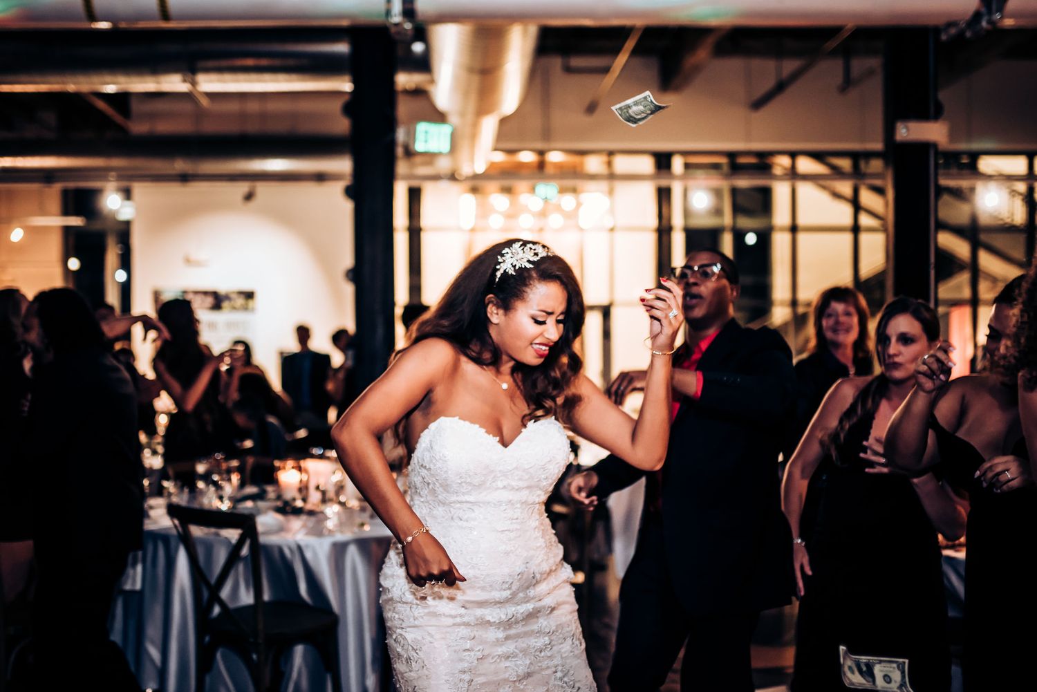 A person in a white wedding dress dances energetically during the reception celebration.