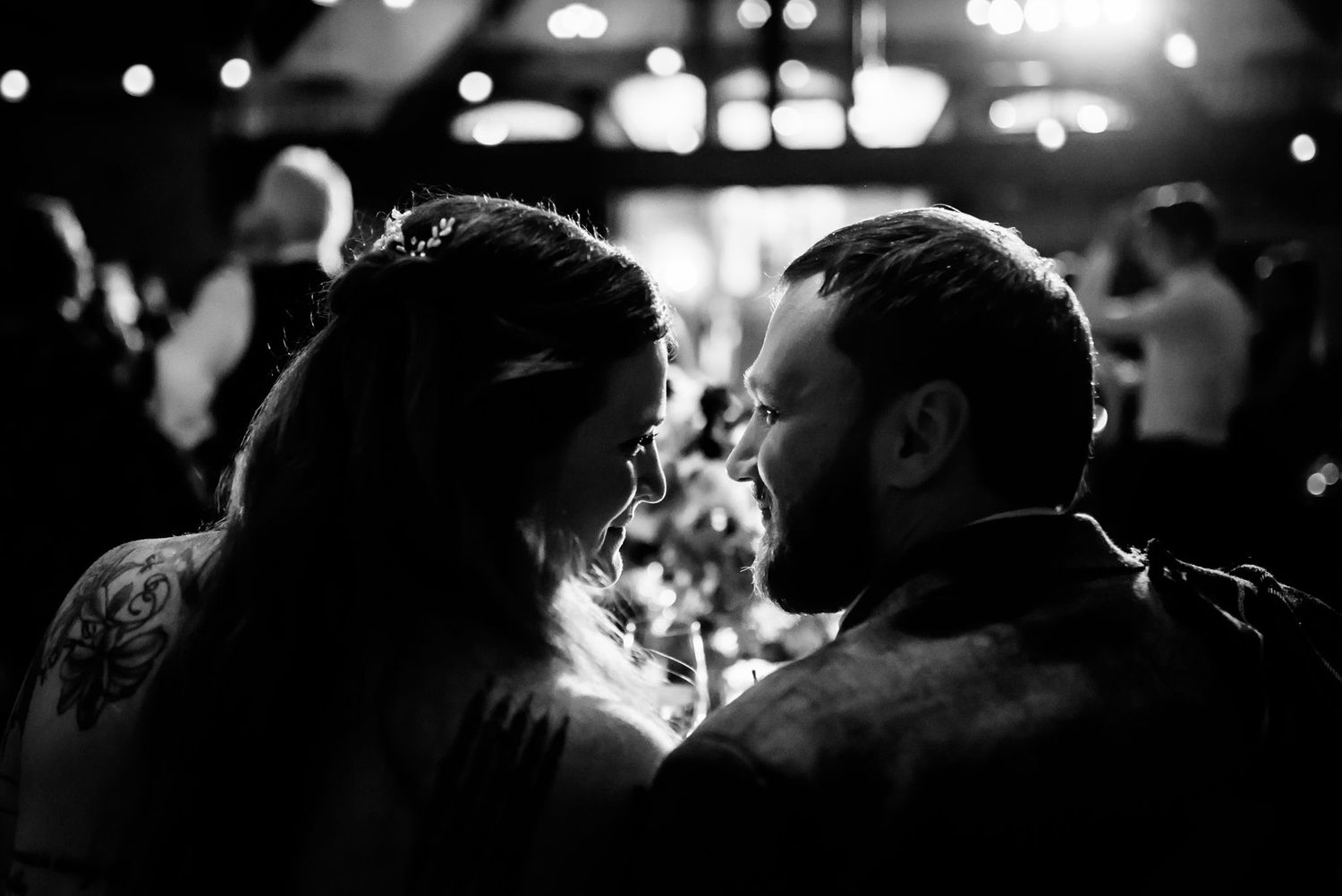 Silhouette of a couple sharing an intimate moment at a dimly lit reception.