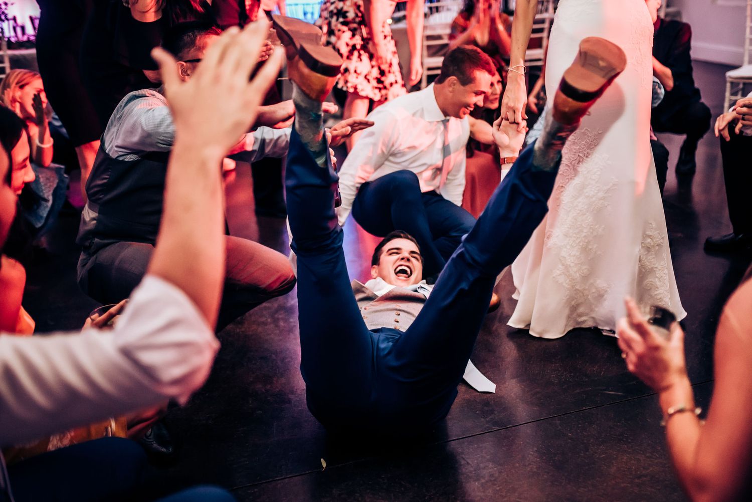Party guests dancing and celebrating with dramatic lighting at a wedding reception.