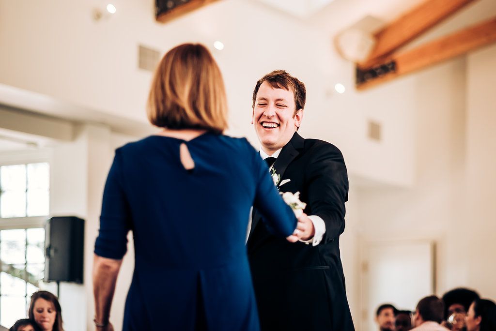Joyful moment between dancers at an elegant indoor wedding reception venue.