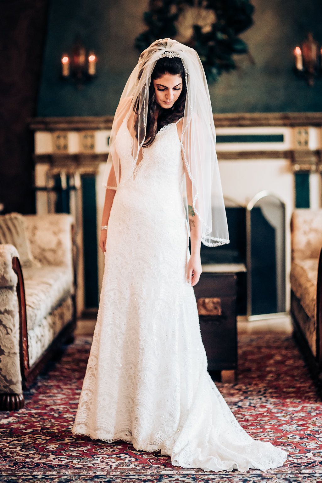 Classic bridal portrait in a white lace gown with flowing veil inside an elegant interior.