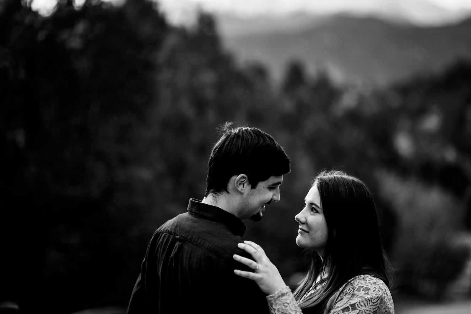 Intimate black and white portrait of couple against mountain landscape.