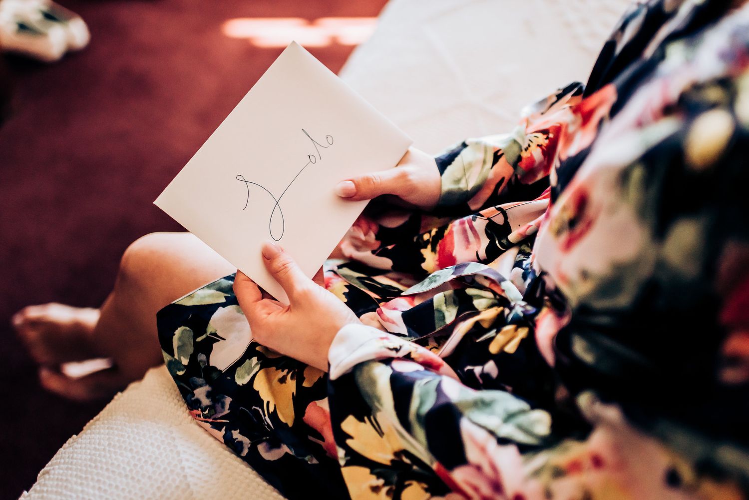 Person in floral robe writing on paper while sitting.