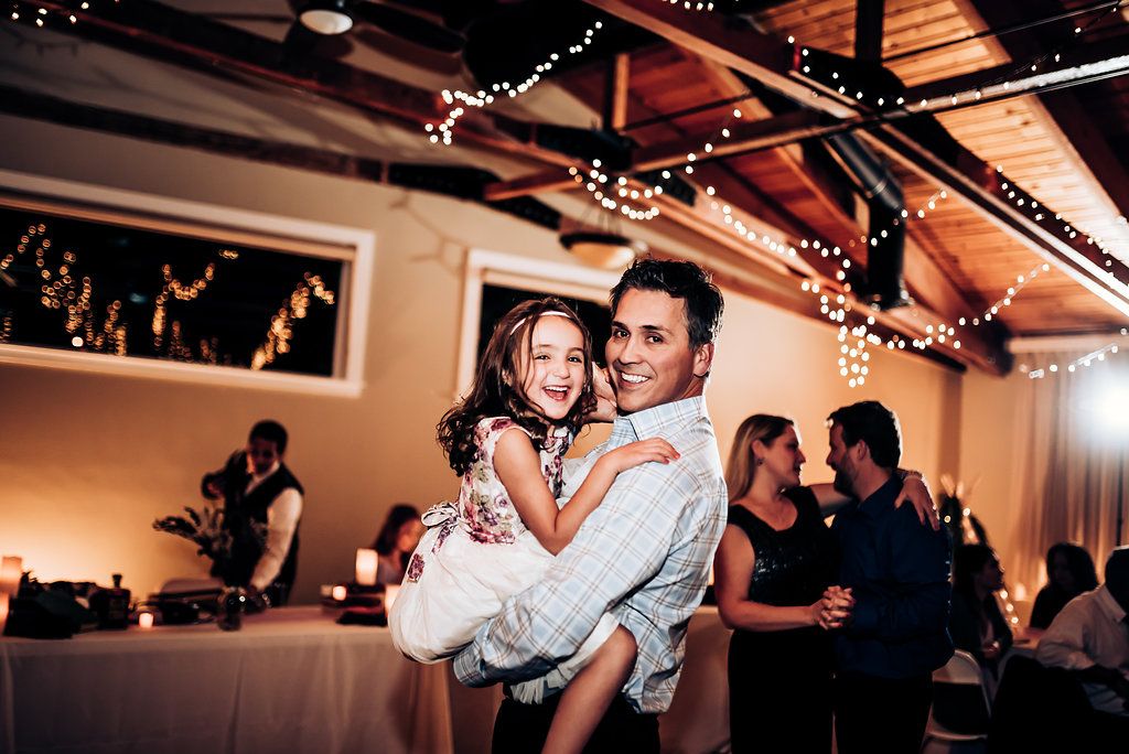 Guests sharing playful dance moment at indoor wedding reception.
