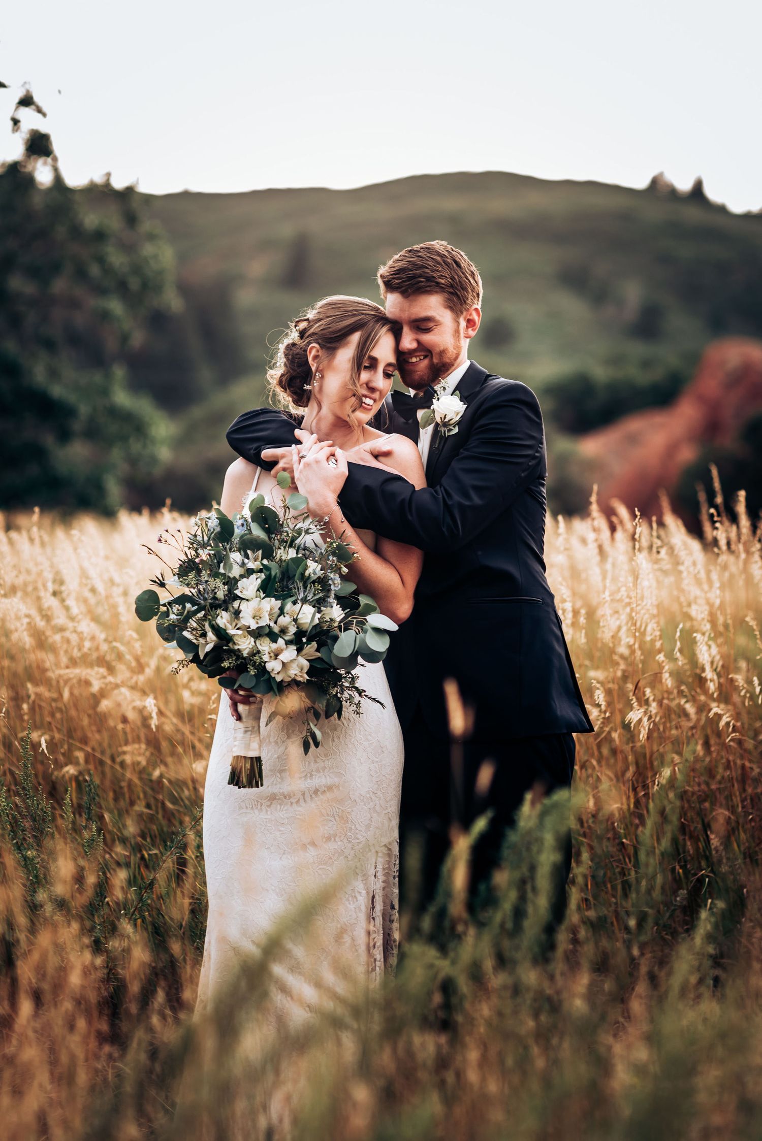 Intimate wedding portrait in golden field with couple sharing tender moment.