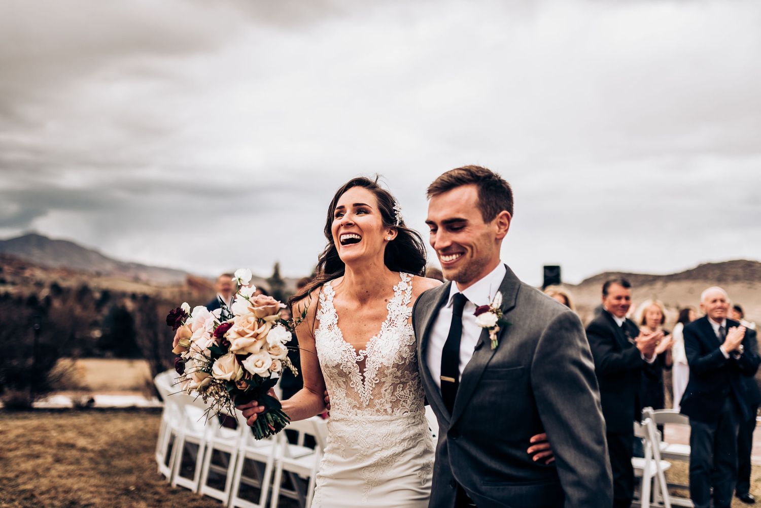 Beaming couple shares a laugh while walking down the aisle after their mountain wedding ceremony.