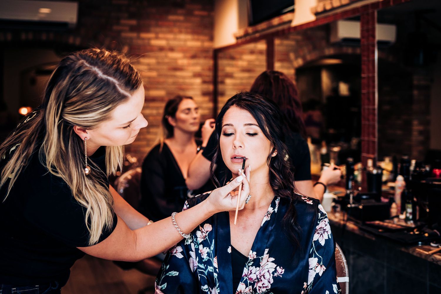 A makeup artist applying cosmetics during pre-wedding preparations.