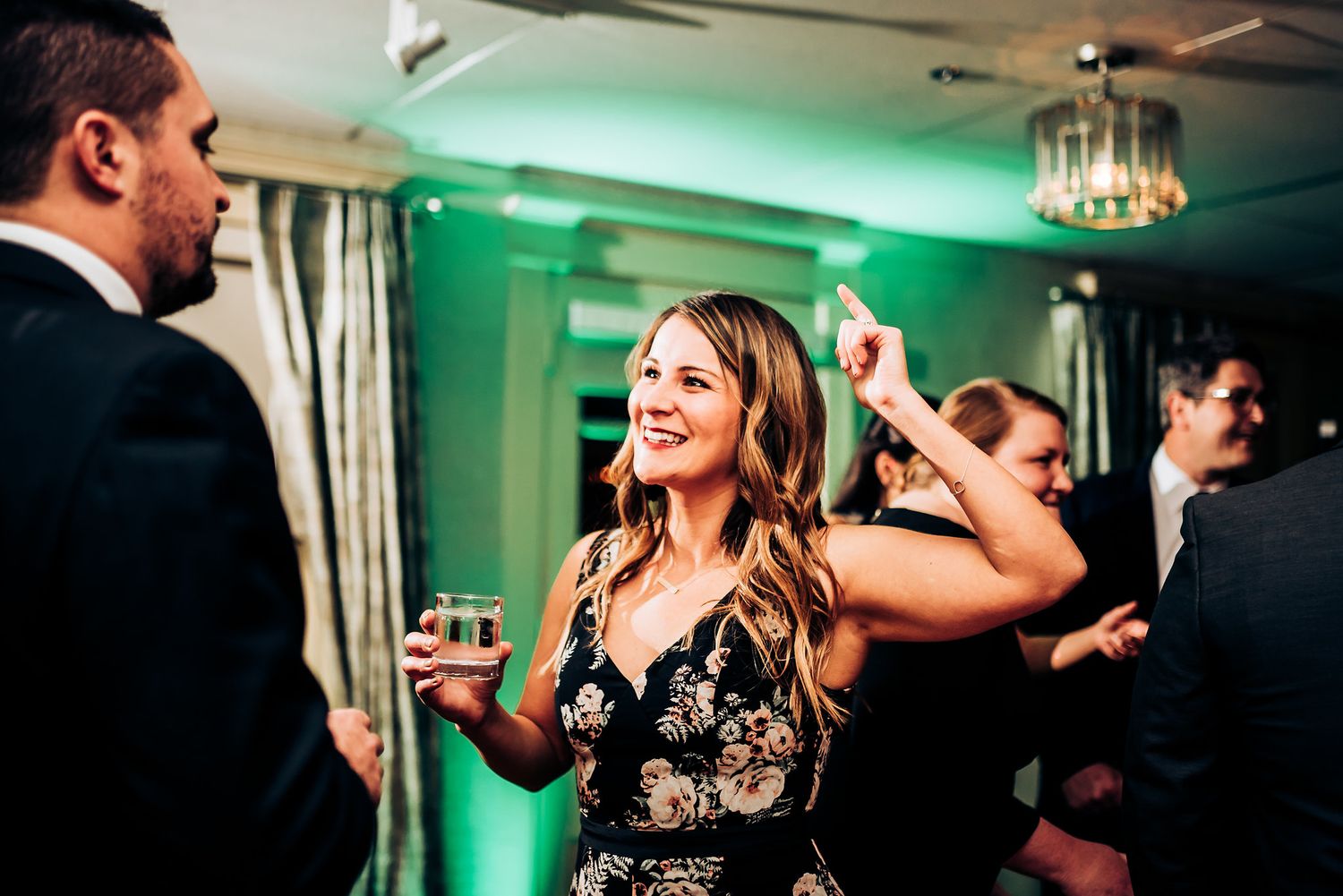 A guest in a black lace dress dances and socializes at an evening event.