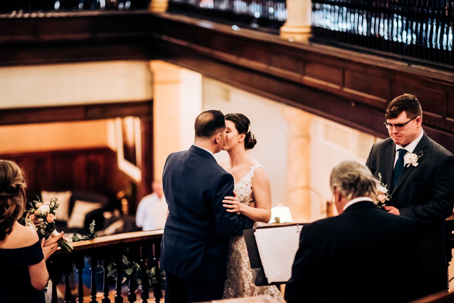 Intimate moment captured during wedding ceremony on vintage wooden staircase landing.