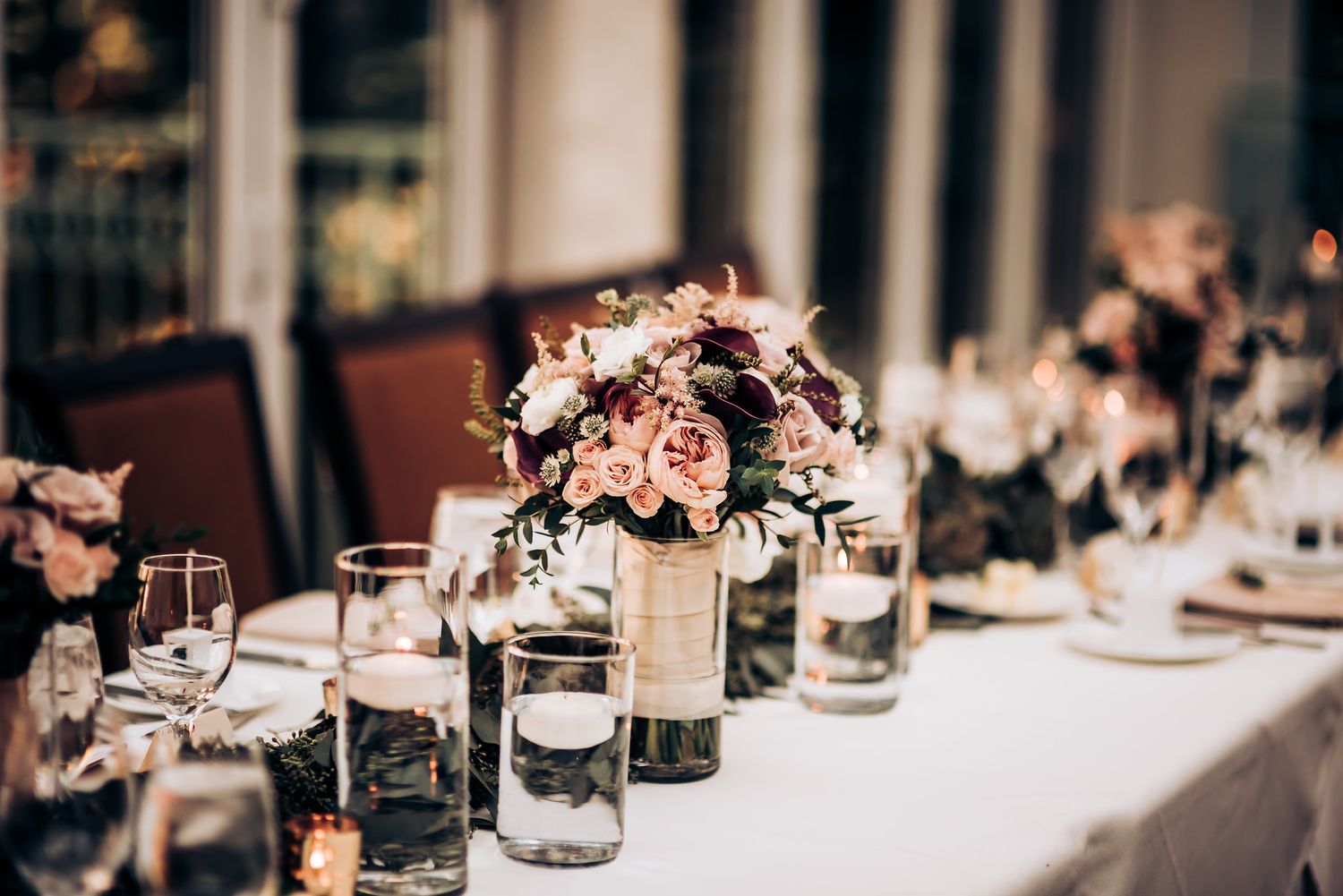 Wedding reception table decor with floral centerpieces and glowing candlelight.