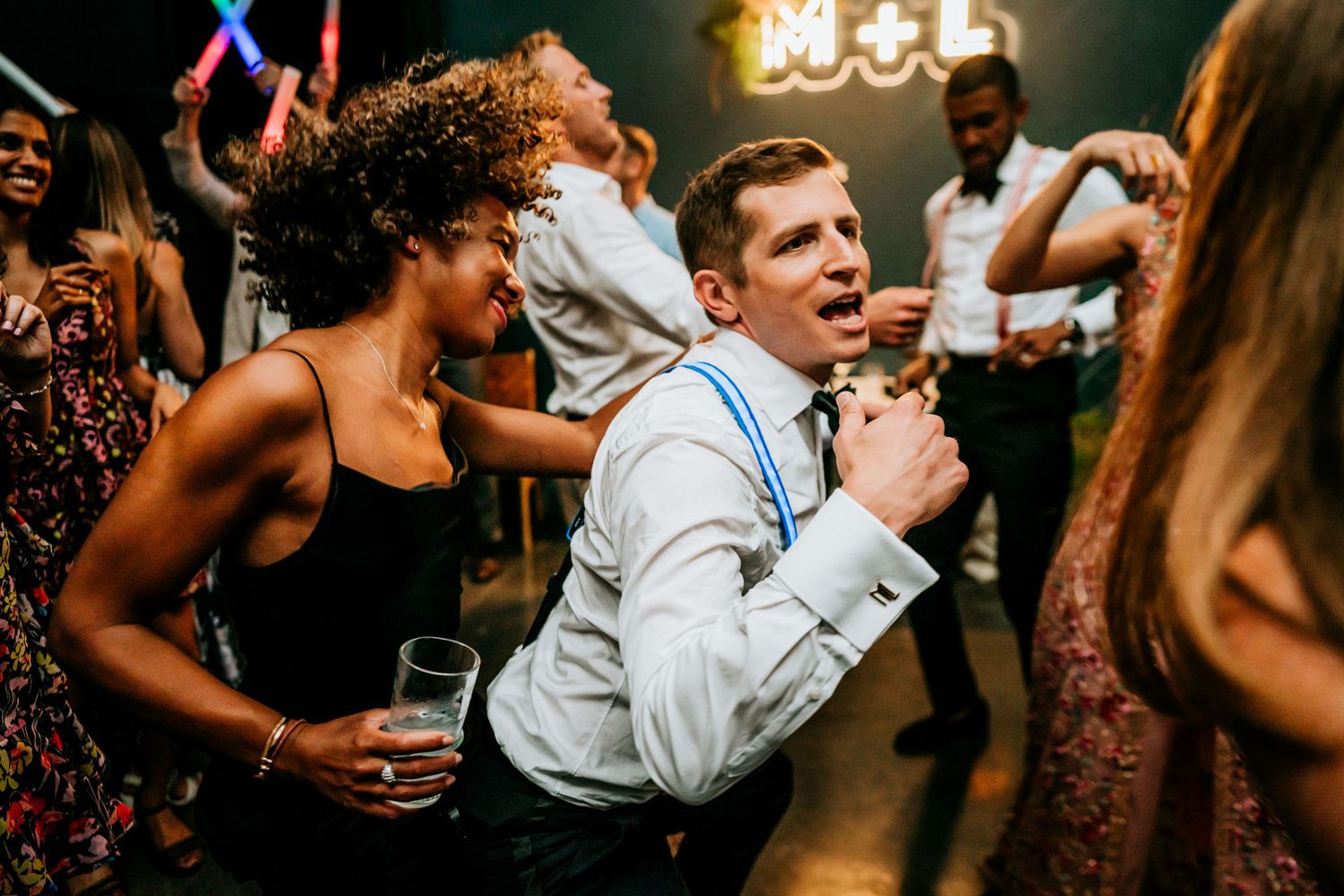 Energetic dance party scene with guests celebrating on a dimly lit dance floor.
