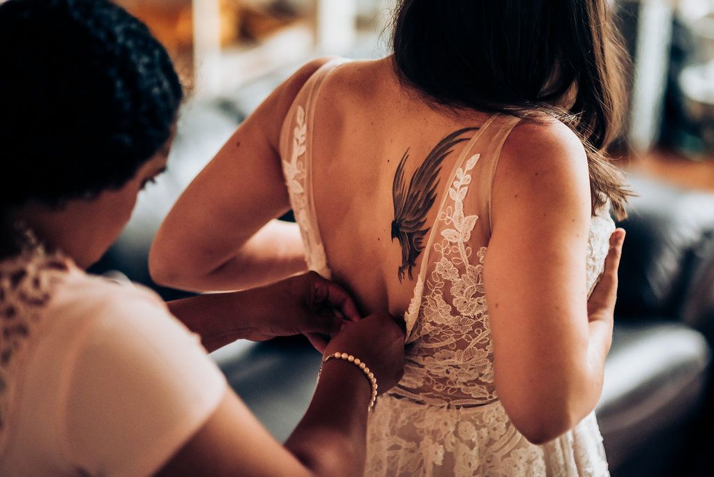 Close-up of intricate lace detail being adjusted on a wedding dress.