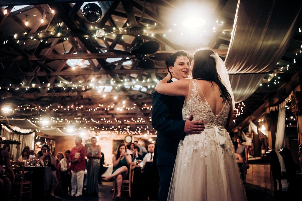 A couple sharing an intimate dance under string lights at their wedding reception.