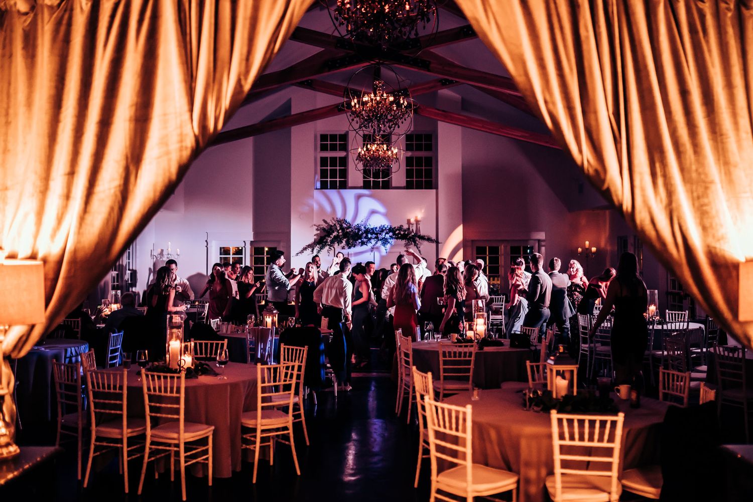 Elegant wedding reception venue with amber uplighting and draped fabric creating a warm atmosphere.
