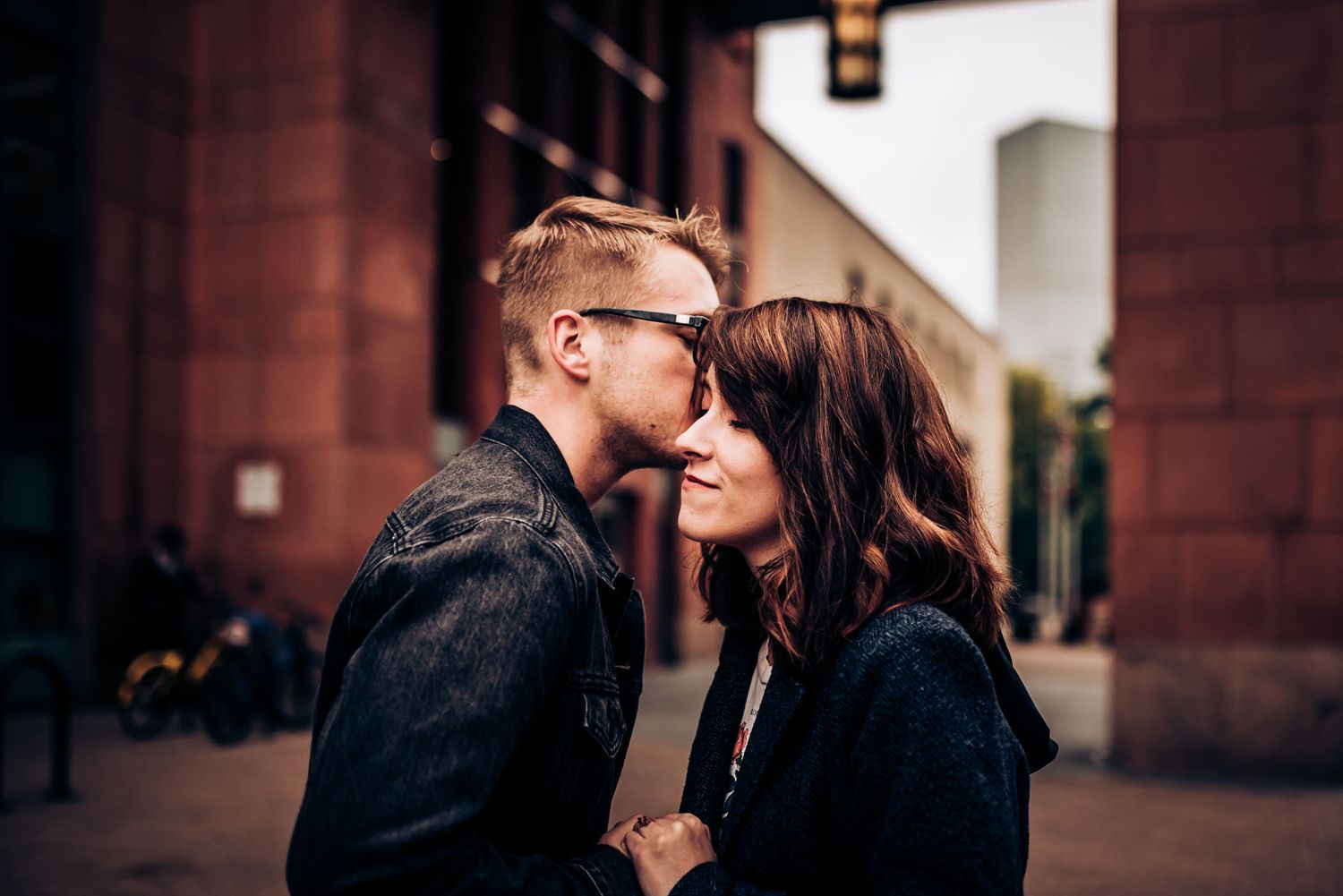 A couple shares a close intimate moment in an urban setting.