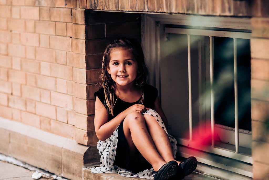 Young guest sits casually by a brick wall and window during a formal event.