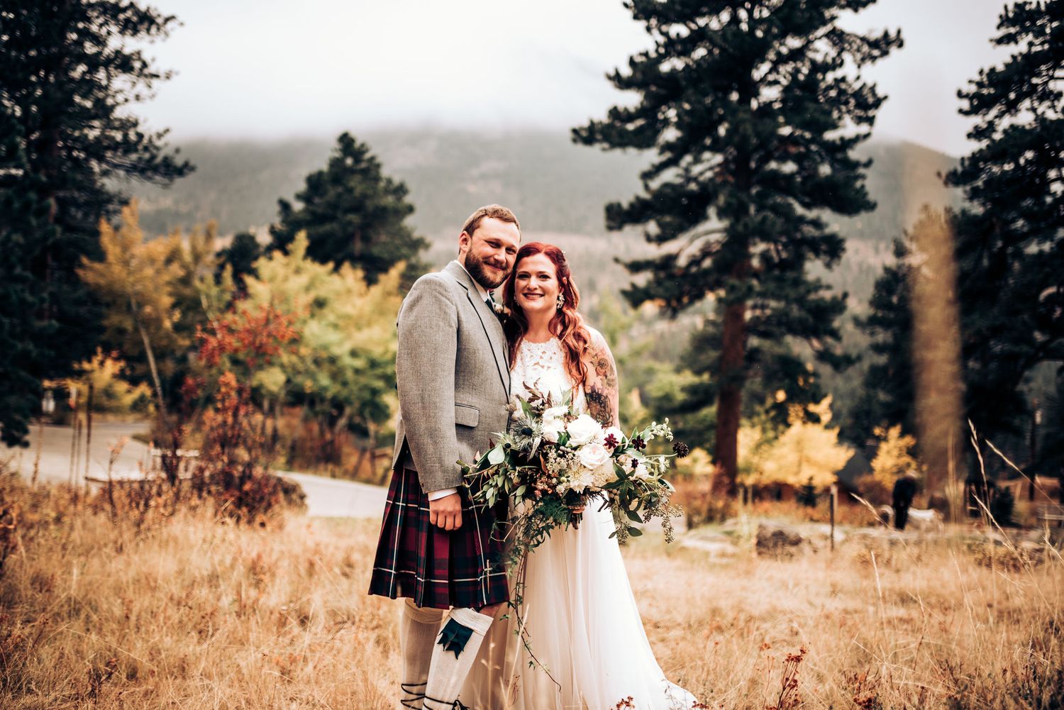 Wedding couple in Scottish formal wear pose in autumn mountain landscape.