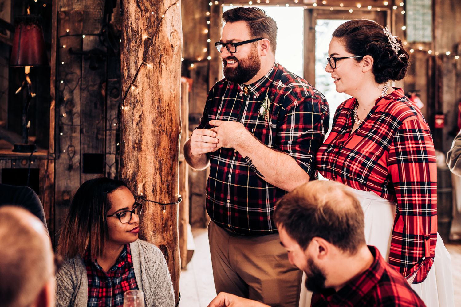 Group in plaid shirts having conversation at rustic indoor venue.