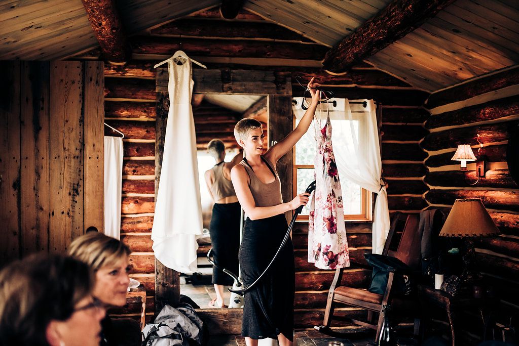 Wedding preparation scene in rustic log cabin interior with hanging dresses.