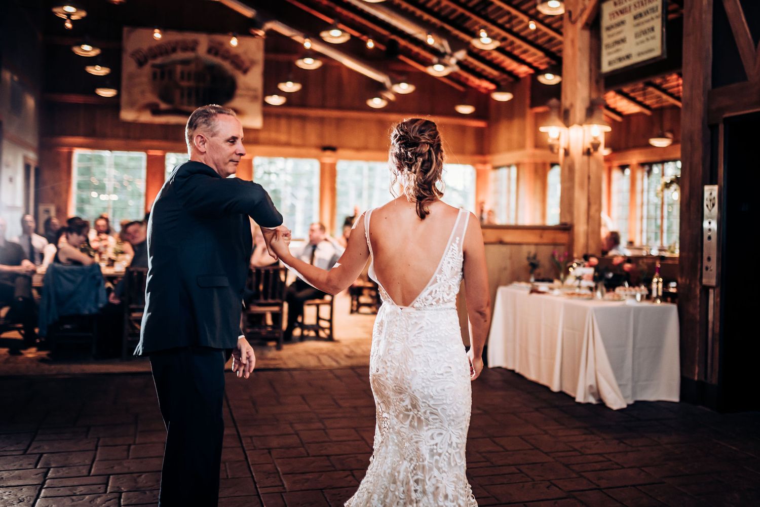 Wedding dance in rustic reception venue with wooden beams and natural light.