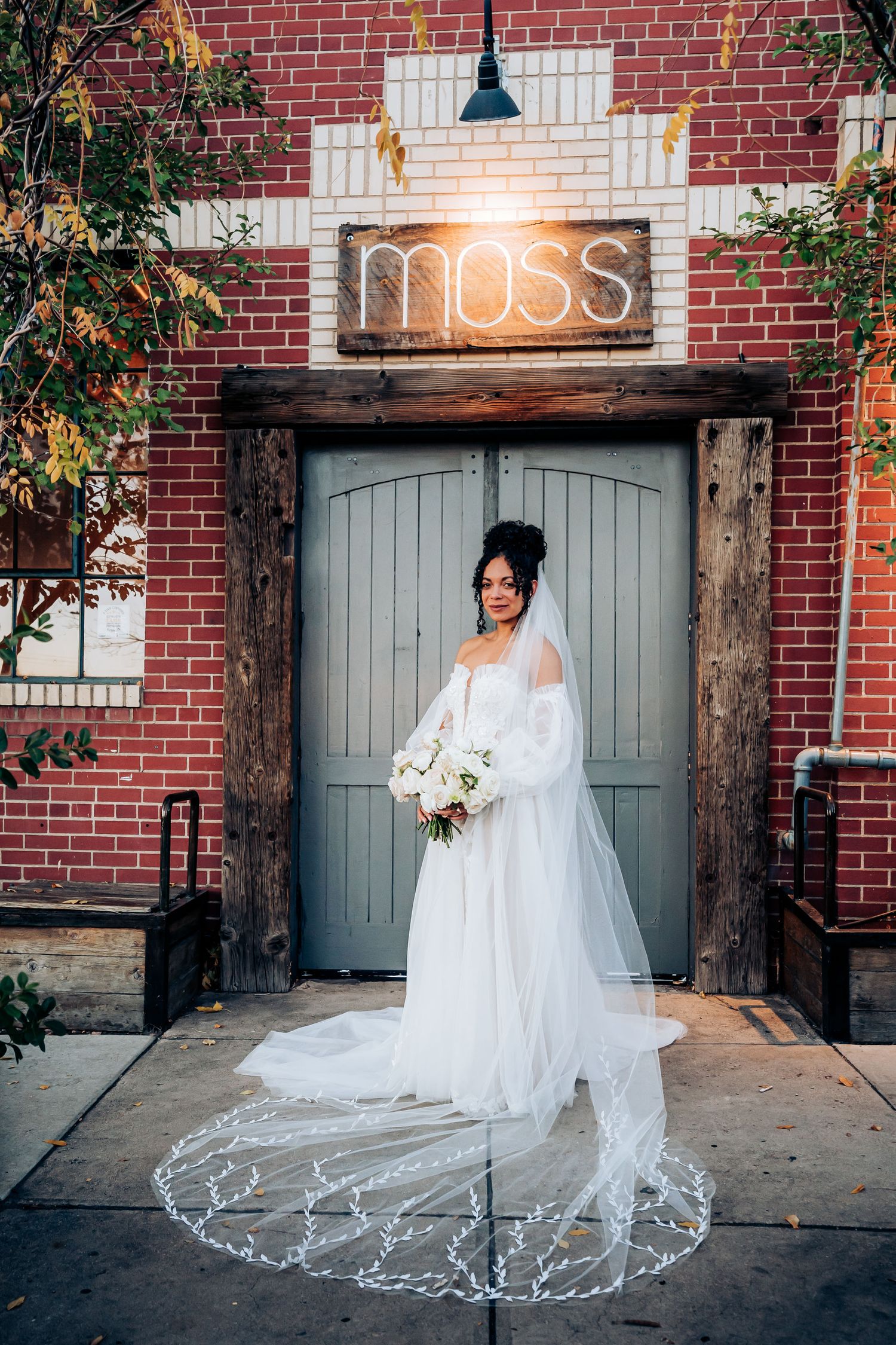 Elegant bridal portrait at Moss venue showcasing intricate lace veil and white bouquet.