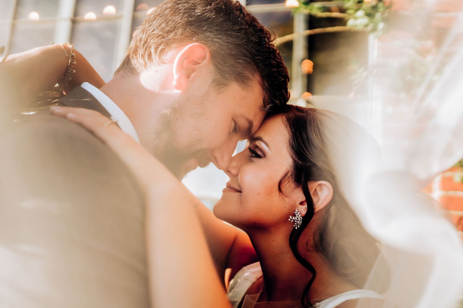 Romantic closeup of newlyweds sharing an intimate moment under soft lighting.